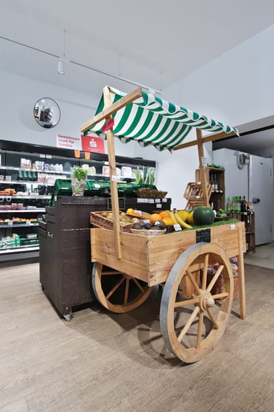 Marktkarren aus Holz mit grün-weißem Dach und Obst im Verkaufsraum